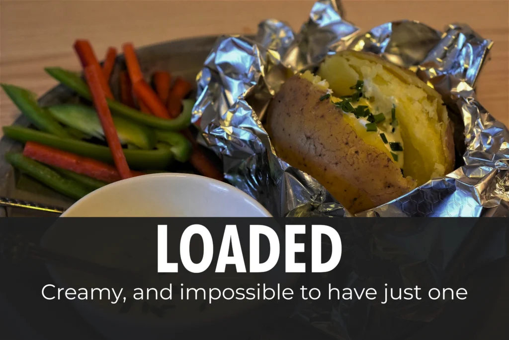 Crispy skin baked potato split open with fluffy white interior, topped with bubbling melted cheddar cheese and baked beans.