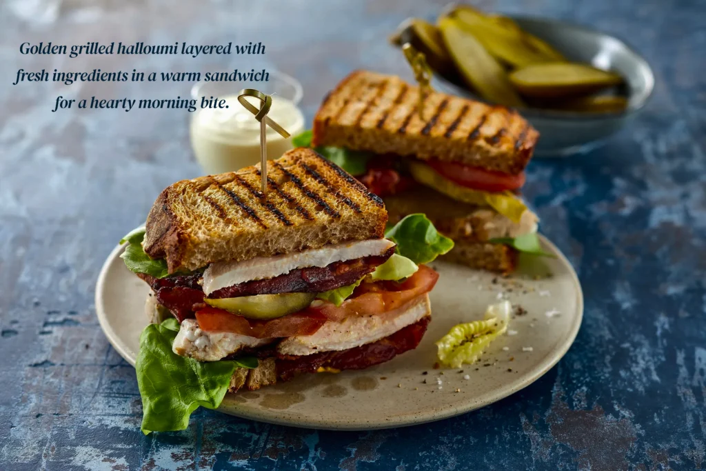 Seared halloumi breakfast sandwich on a toasted brioche bun with a fried egg, avocado slices, and chili jam.