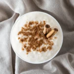 A spoonful of thick, vanilla-scented rice pudding showing the tender grains and creamy texture.