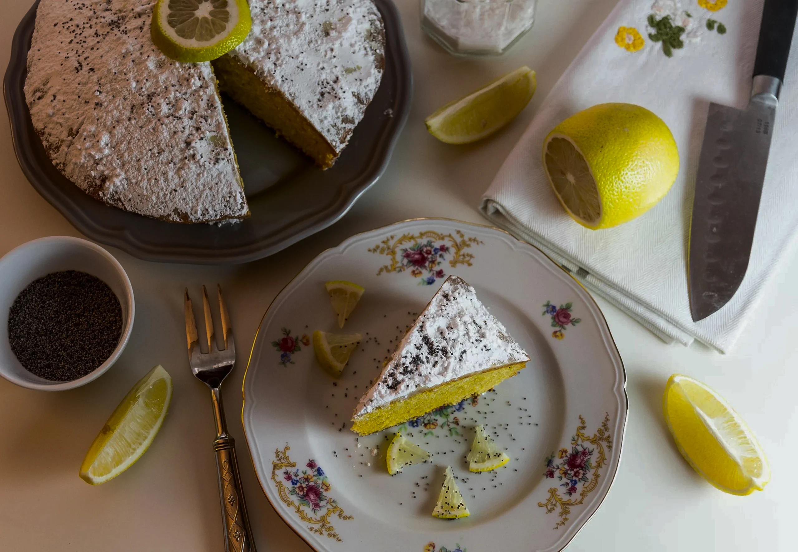 A thick slice of moist lemon loaf cake on a white plate, showing the saturated "drizzle" layer near the top crust.