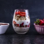 Close-up of a strawberry Eton Mess showing the texture of crisp meringue pieces folded into thick vanilla cream.