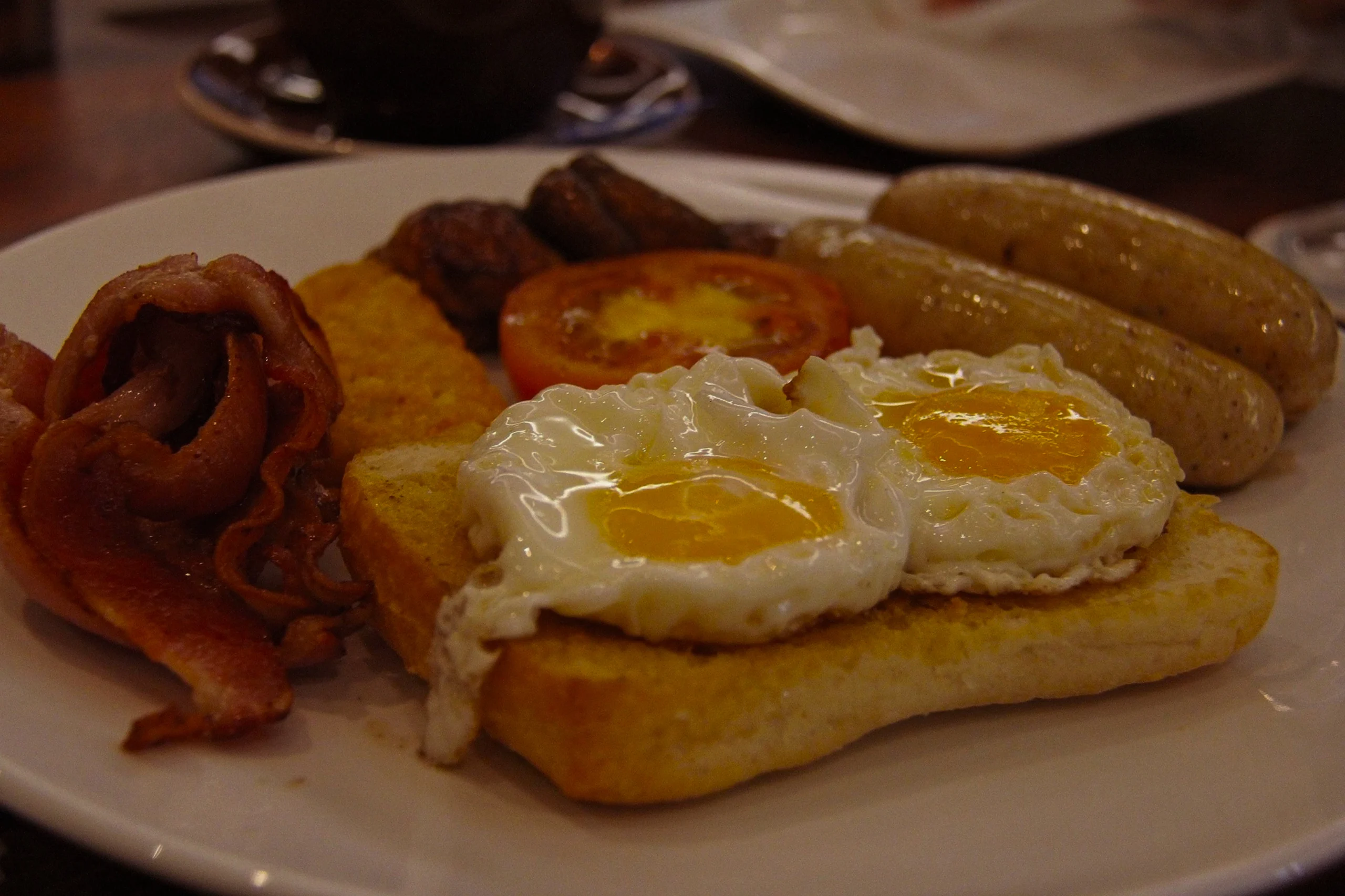Traditional British fry-up breakfast plate served with buttered toast and a cup of English breakfast tea.