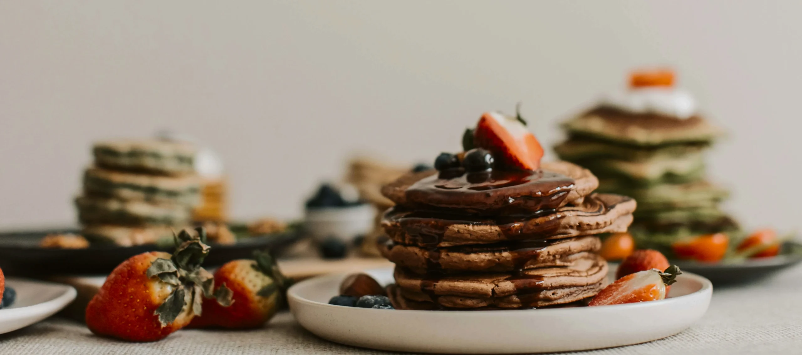 Thick buttermilk pancakes dusted with powdered sugar and garnished with edible flowers on a ceramic plate.