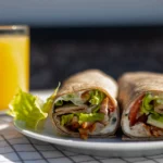Close-up of a protein-packed breakfast wrap with Cumberland sausage, avocado, and a spicy tomato salsa.