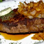 Juicy pan-seared ribeye steak with a side of crispy fries and homemade green peppercorn gravy.