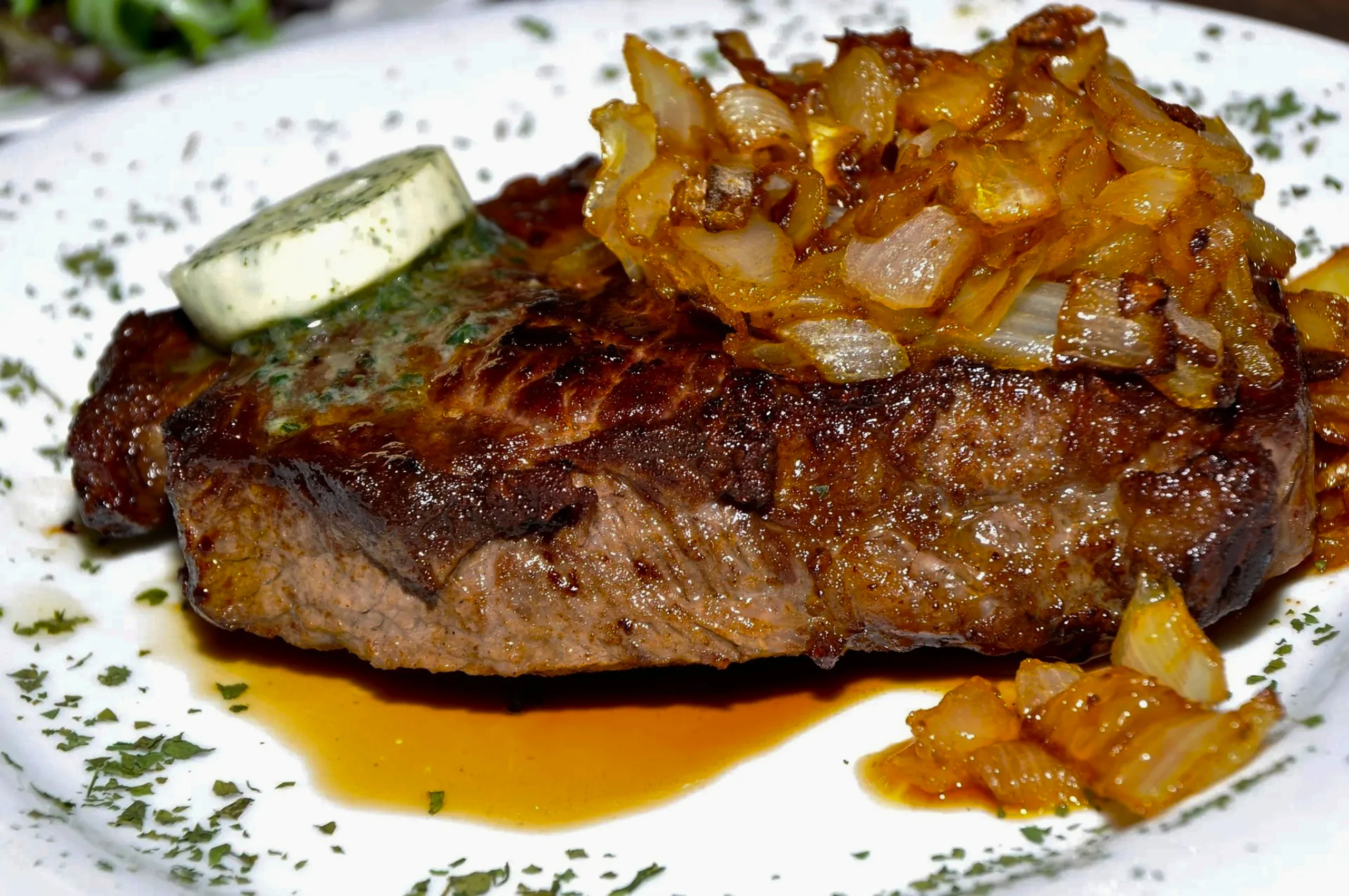 Juicy pan-seared ribeye steak with a side of crispy fries and homemade green peppercorn gravy.