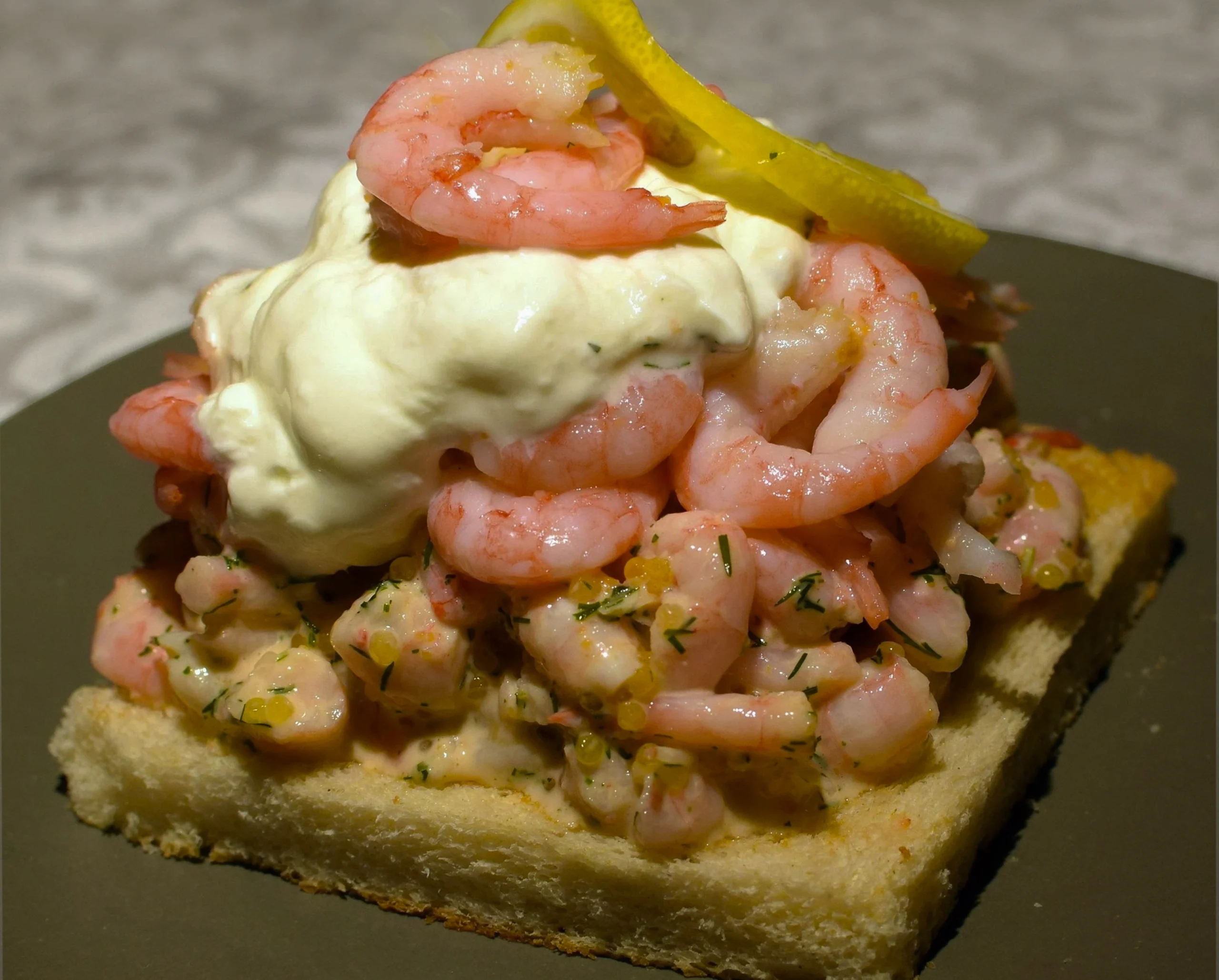 A gourmet prawn mayonnaise sandwich on thick-cut malted bloomer bread with fresh baby gem lettuce and a light dusting of smoked paprika on a rustic plate.