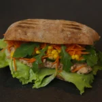 Close-up of tuna mayo and sweetcorn filling with red onion and black pepper on a soft white bloomer.