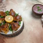 Spicy Peri-Peri Chicken thighs grilled to perfection with charred skin and a vibrant red chili bird's eye pepper sauce garnish.