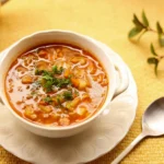 Close-up of a spoonful of velvety potato leek soup with crispy bacon bits and cracked black pepper.