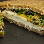 Close-up of creamy egg mayonnaise with fresh cress on a buttered brown bloomer slice.