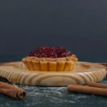 Slice of treacle tart showing the thick, sticky breadcrumb and golden syrup filling inside a buttery shortcrust pastry.