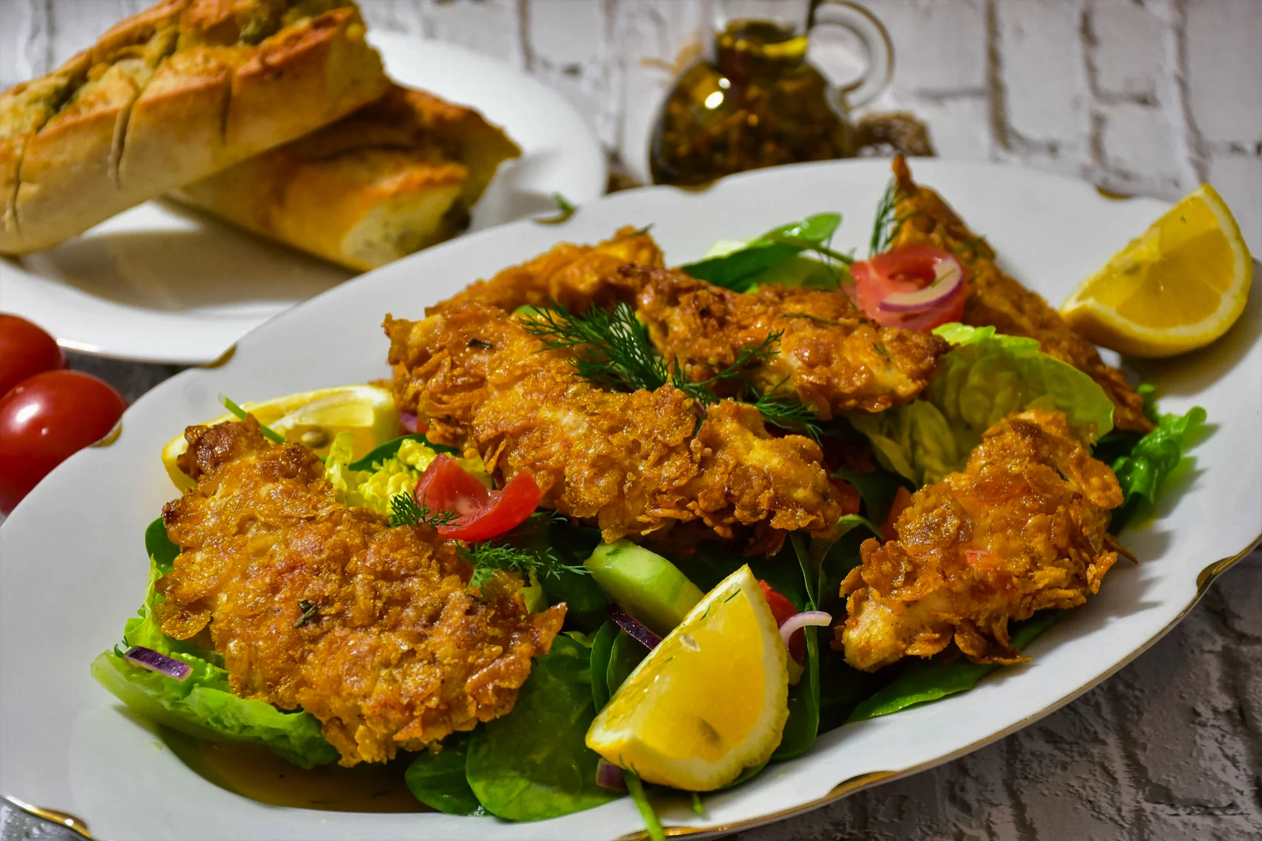Close-up of golden-brown fried chicken strips on a bed of fresh romaine lettuce with a drizzle of Caesar sauce.