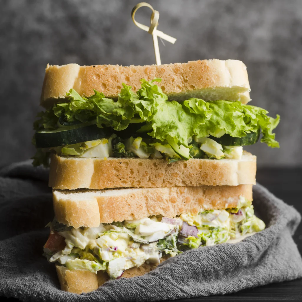 Classic egg sandwich with a thick, creamy mayo filling and chopped herbs on soft bread