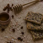 Close-up of a stack of homemade honey oat bars showing whole almonds, flax seeds, and a honey glaze.