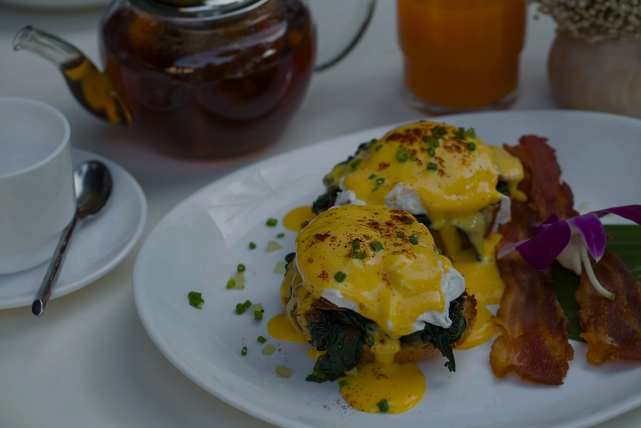 Close-up of traditional Eggs Benedict with Canadian bacon and runny egg yolk, showing how to layer the brunch classic.