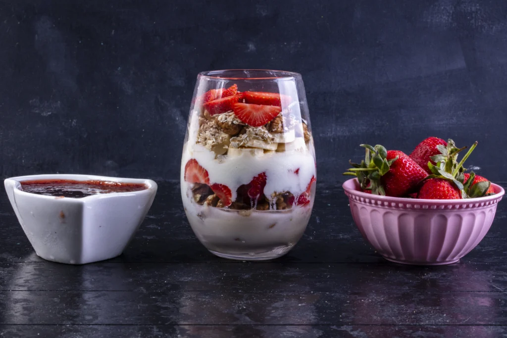 A close-up shot of a spoon dipping into a bowl of Eton Mess, showing the airy texture of whipped cream mixed with juicy berry juices and crunchy meringue shards