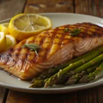 A plate of grilled salmon with lemon slices, fresh dill, and melted herb butter on a white ceramic plate.