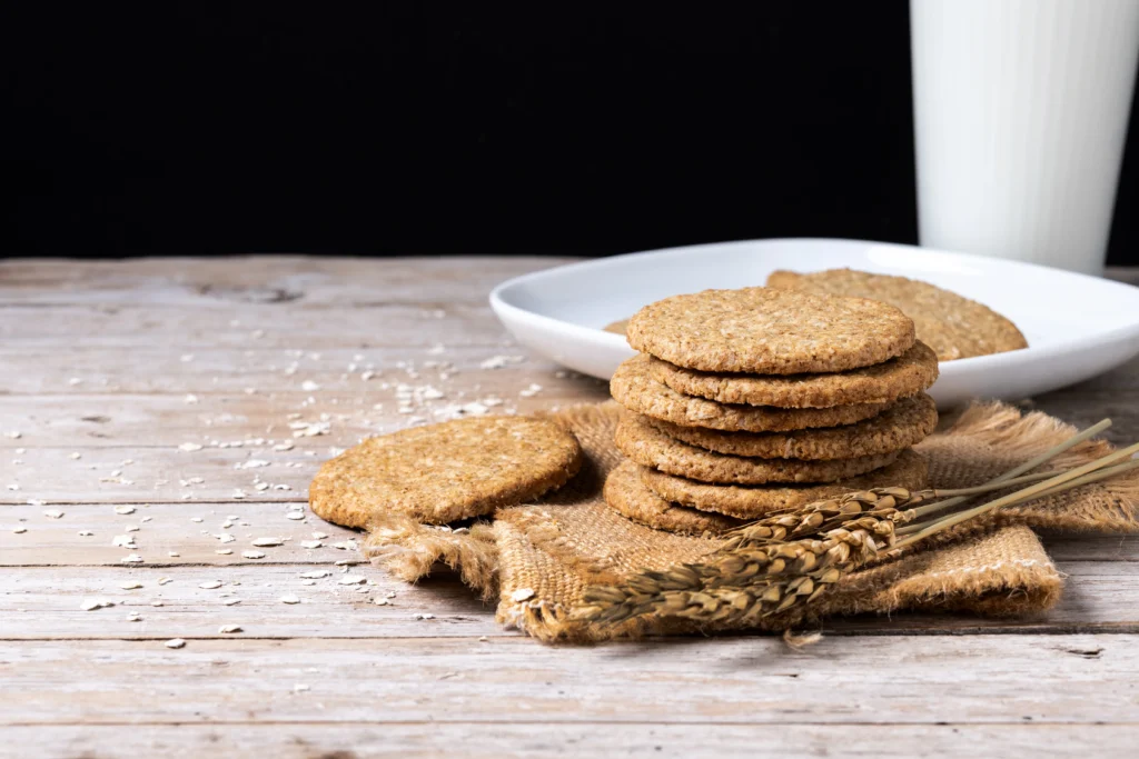 Wholewheat digestive biscuits with dark chocolate coating on a rustic wooden background