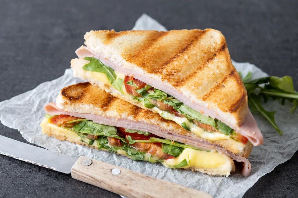Classic grilled cheese and tomato sandwich on a rustic plate, served with a side of creamy tomato soup