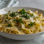 Close-up of golden brown sliced mushrooms tucked into a silky parmesan cream sauce over pasta noodles.