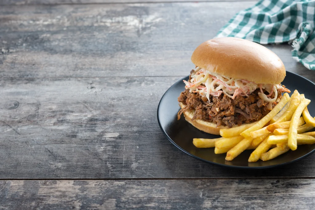 Smoky Sloppy Joe sandwich with bold BBQ sauce and melted cheddar on a rustic wooden board