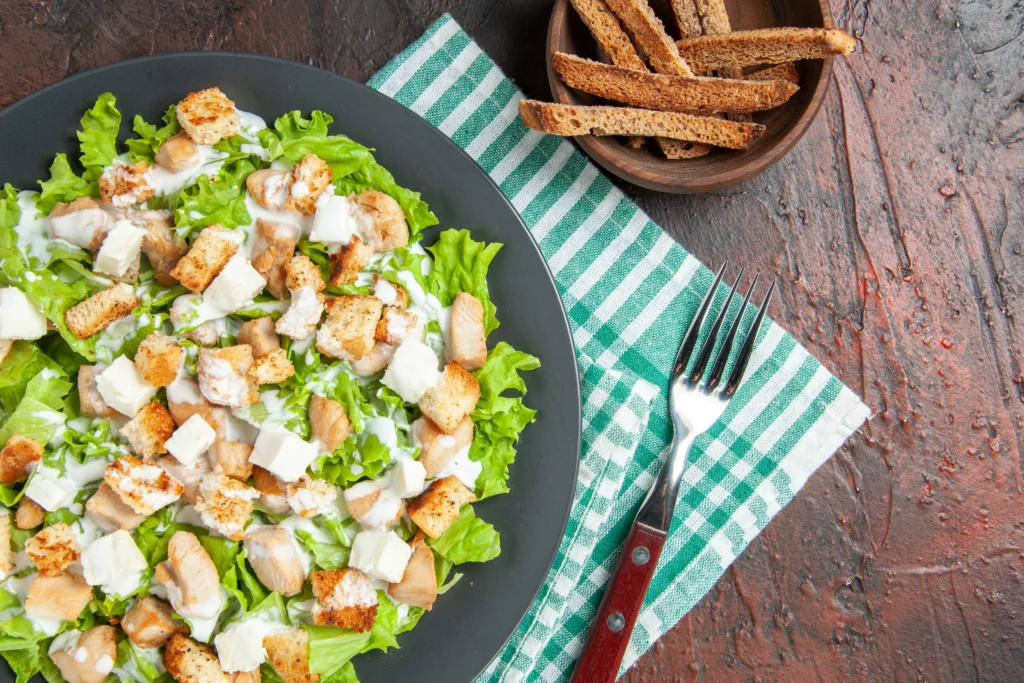 Fresh Caesar salad topped with shaved Parmesan and homemade croutons in a chilled ceramic bowl