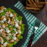 Close-up of a Caesar salad bowl topped with freshly cracked black pepper and a lemon wedge