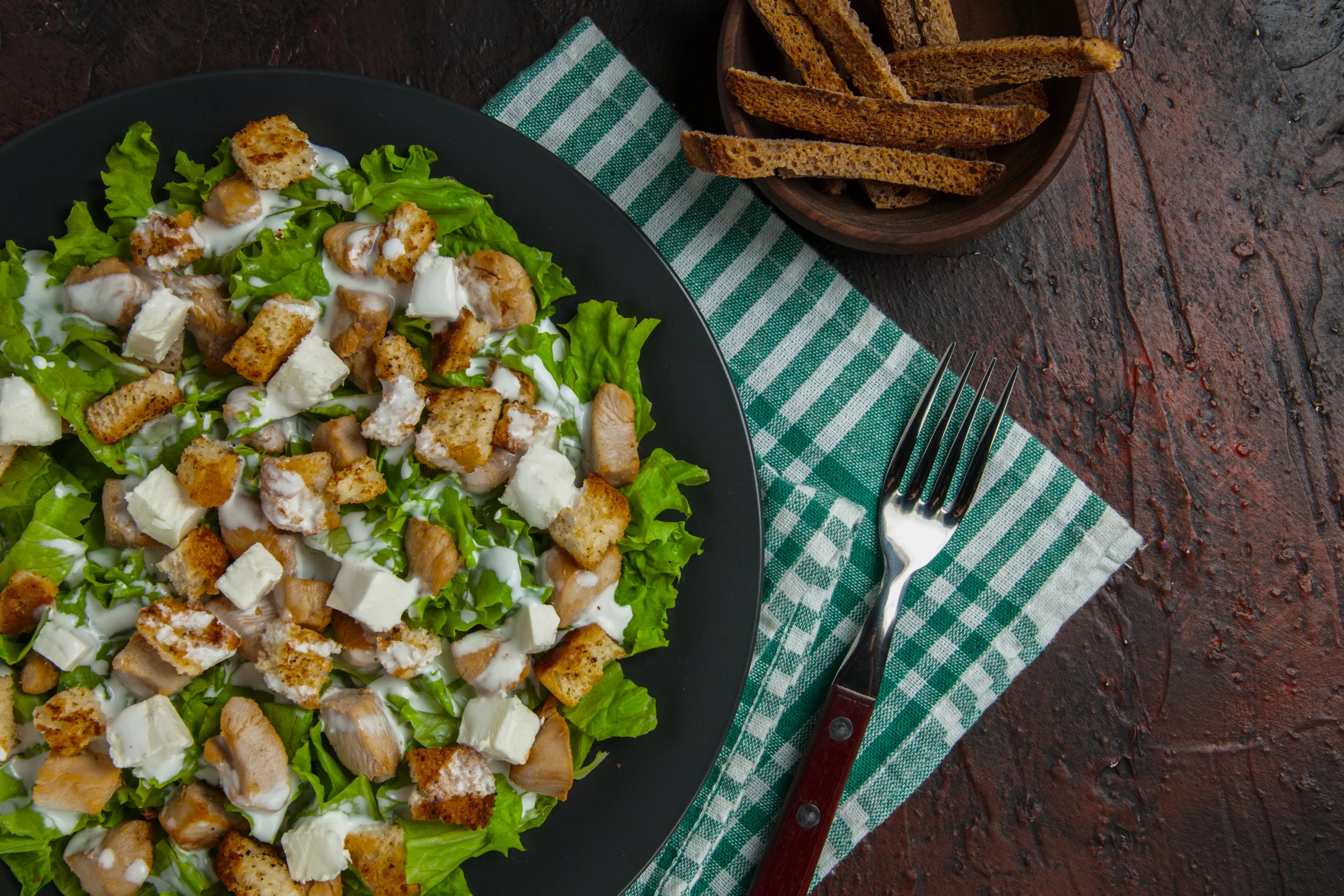Close-up of a Caesar salad bowl topped with freshly cracked black pepper and a lemon wedge
