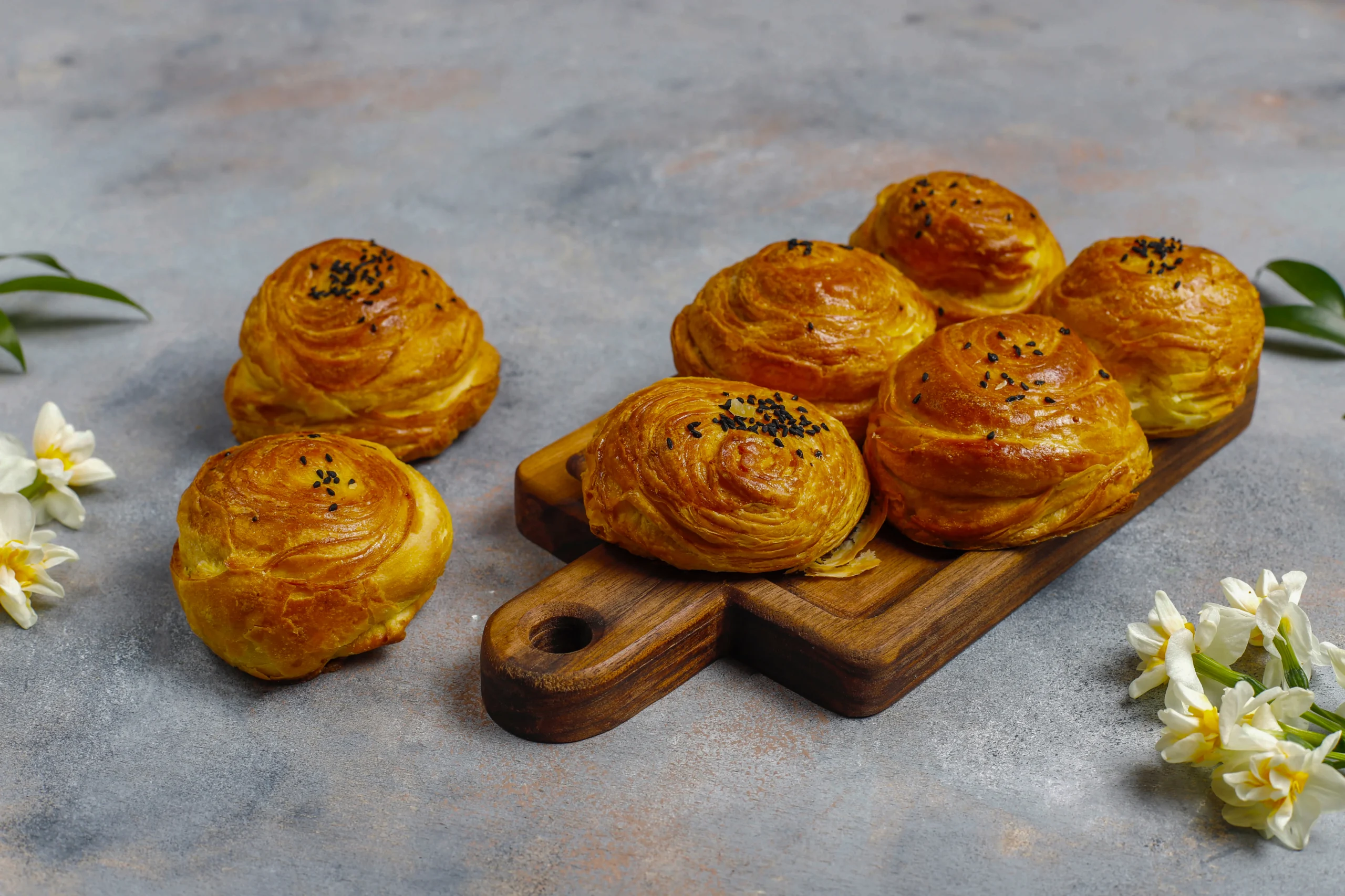 A stack of buttery puff pastry squares showing the lamination and 1-inch lift, styled with a linen napkin and a dusting of flour.