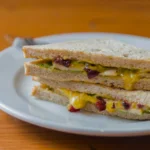 Close-up of a toasted breakfast sandwich showing melted American cheese over a perfectly seasoned over-easy egg.