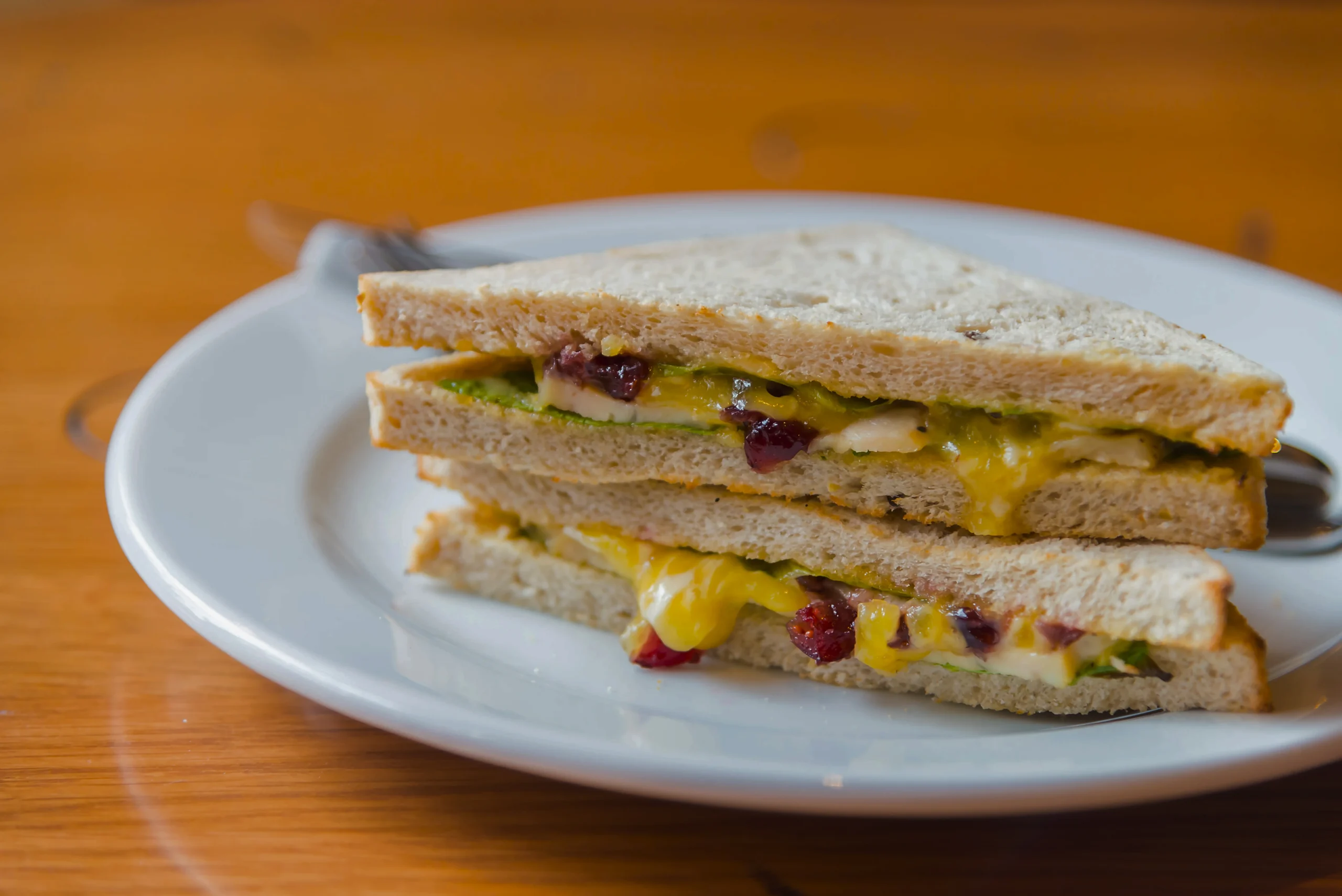 Close-up of a toasted breakfast sandwich showing melted American cheese over a perfectly seasoned over-easy egg.