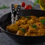 Authentic butter chicken served in a copper bowl with charred garlic naan and a side of basmati rice.