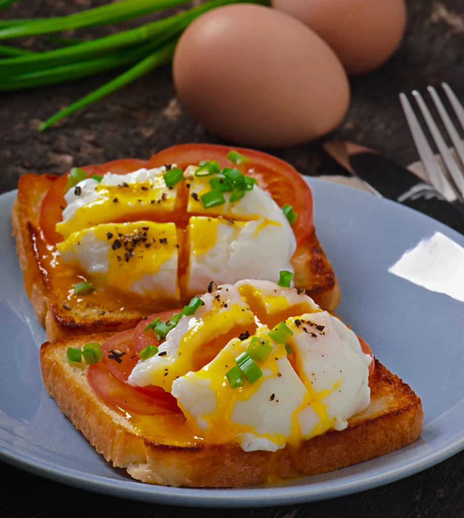 Two soft-boiled eggs with deep orange runny yolks served in marble egg cups alongside thick-cut toasted challah bread soldiers and a pinch of Maldon sea salt.