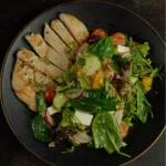 Close-up of a grilled chicken quinoa bowl served in a white bowl with lemon wedge