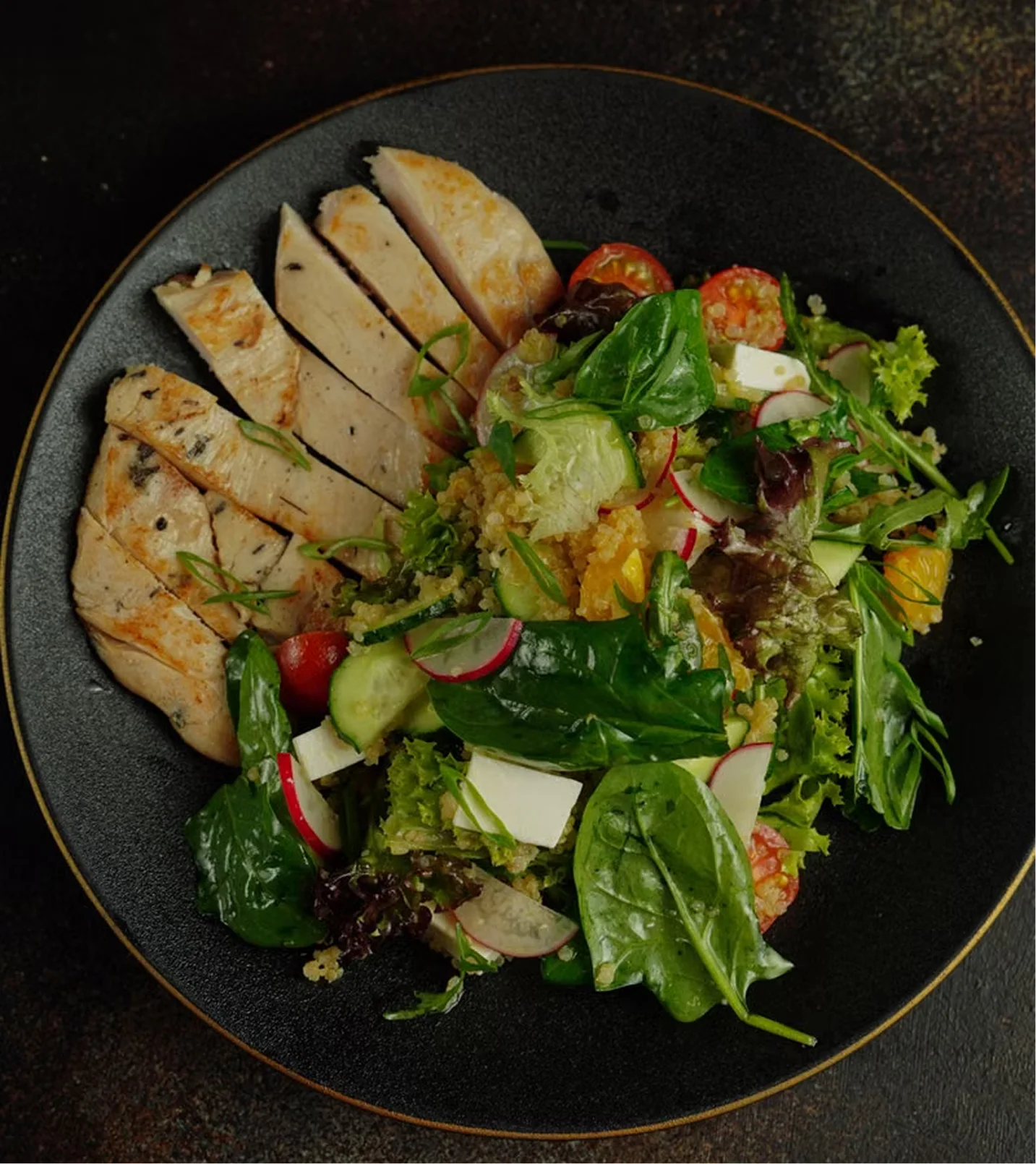 Close-up of a grilled chicken quinoa bowl served in a white bowl with lemon wedge