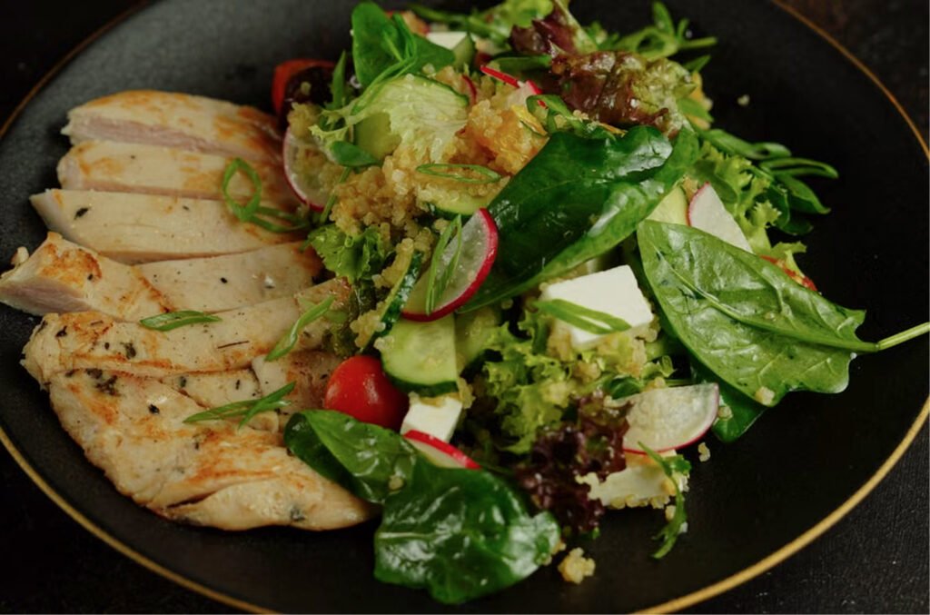 Grilled chicken quinoa bowl with sliced chicken, avocado, cucumber, and lemon dressing