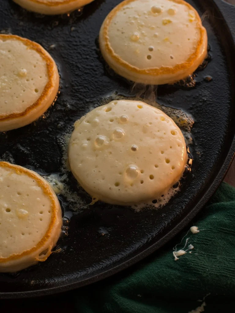 image 5 Scotch pancake batter cooking on a hot griddle, edges turning golden