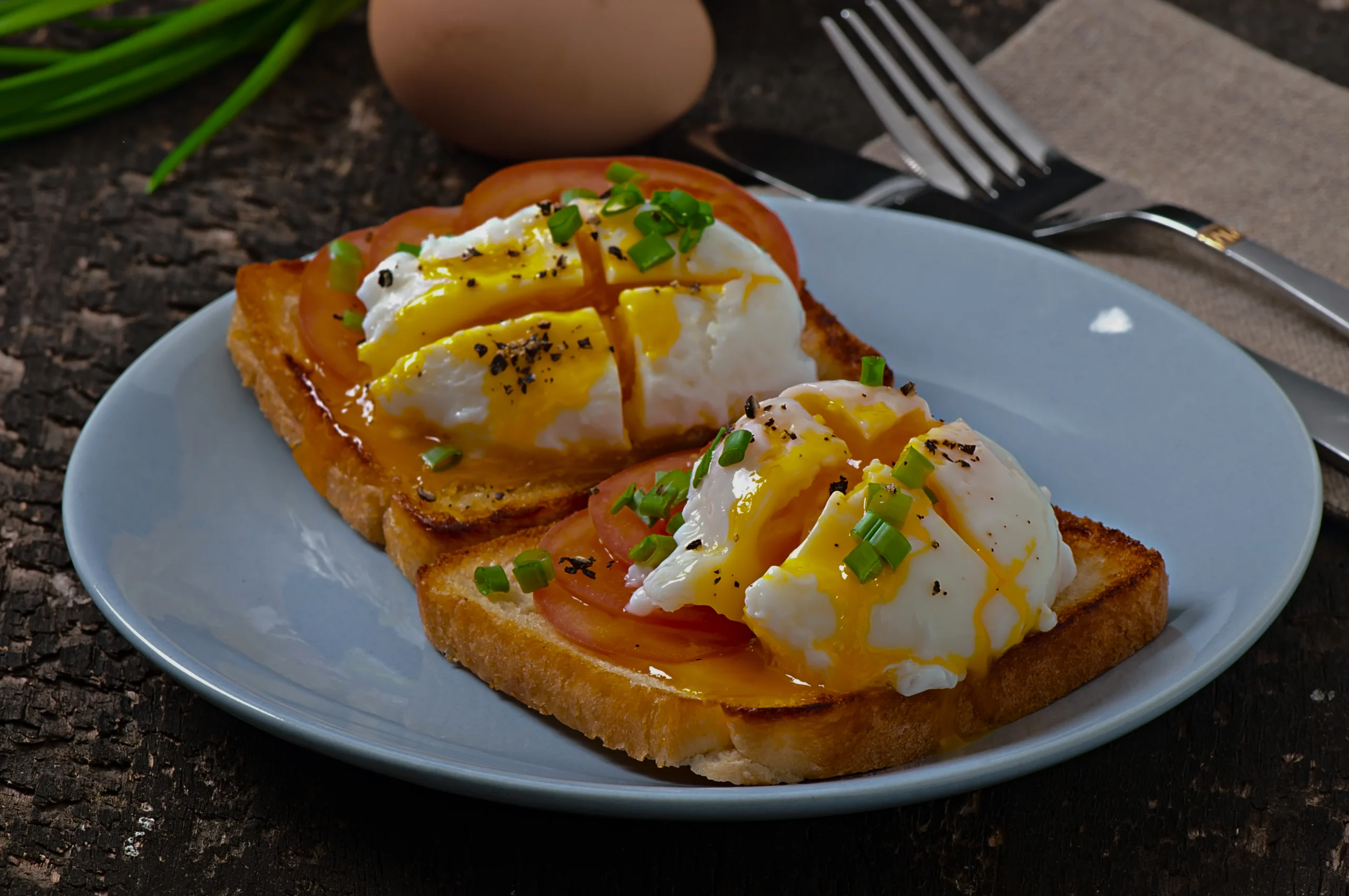 Close-up of a perfectly cooked soft-boiled egg with a jammy yolk and crispy buttered bread strips on a white plate.
