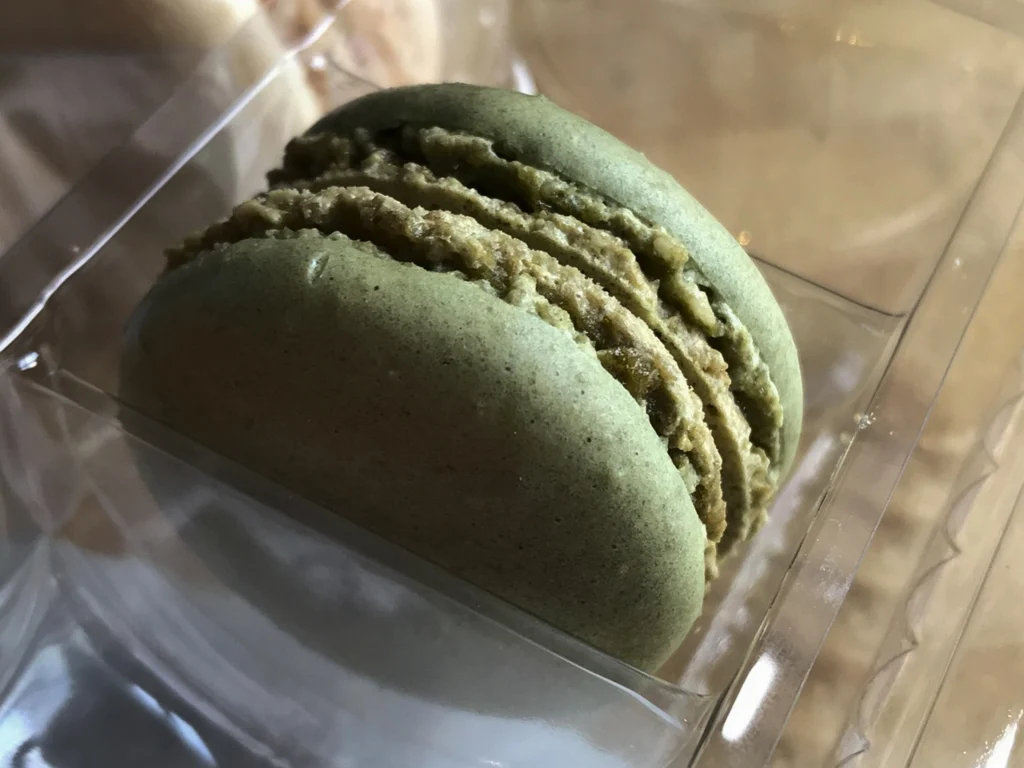 Close-up of pistachio macarons showing crisp shells and rich white chocolate pistachio filling with a soft chewy center