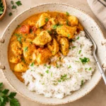 Creamy coconut chicken curry with tender chicken in a rich coconut sauce, garnished with fresh coriander and served with basmati rice.